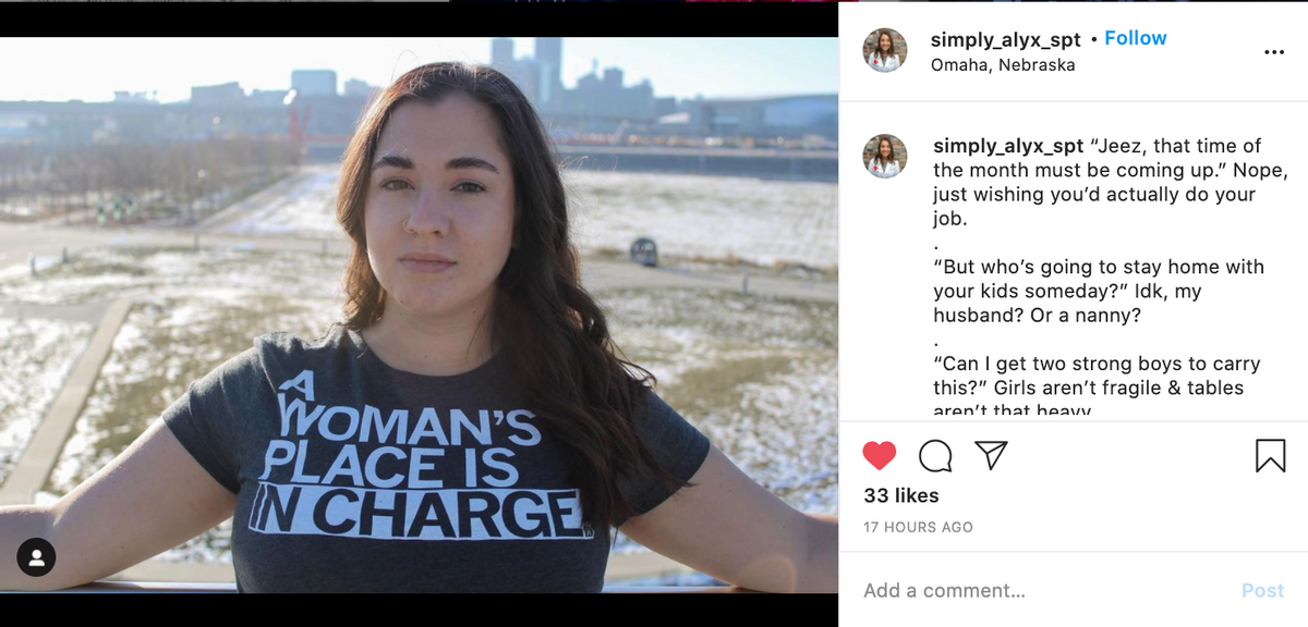 A woman looking at the camera wearing a union made, dark gray T-shirt that reads, A woman’s place is in charge.