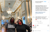 Two women wearing face masks stand inside an elegant, sweatshop-free retail shop with chandeliers and ornate molding.